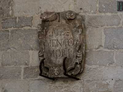 Ai lati del portone sono presenti due stemmi. Il primo reca la scritta Memento Mori (�Ricordati che devi morire�)...